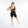 Marathon knee high compression socks with brightly colored stripes in blue, purple, pink ,and yellow - rear view on model